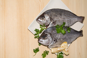 fresh bream or sea bream on the plate with parsley and lemon