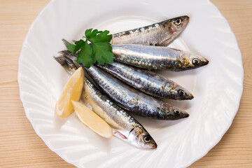 plate of fresh sardines with parsley and lemon on the plate