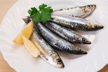 plate of fresh sardines with parsley and lemon on the plate