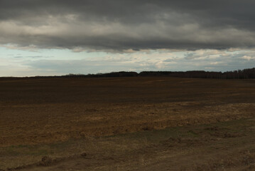 Fototapeta na wymiar Horizon over agricultural fields in the evening. Overcast landscape.