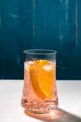 Cold summer delicious coctail with lime and ice in a glass with drops on the white and blue background.