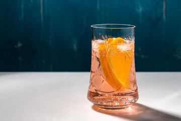 Cold summer delicious coctail with lime and ice in a glass with drops on the white and blue background.