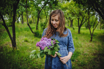 Expectation of the child. Pregnant woman in a park, meadow in the spring with a bouquet of flowers of lilac. Close up. Nine months. The concept of motherhood. Happy mama.