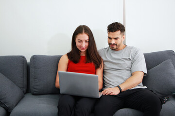 Smiling Caucasian Couple sitting on sofa and working for online business on laptop in social media technology . Work from home and Covid 19 virus is spreading around the world Concept.