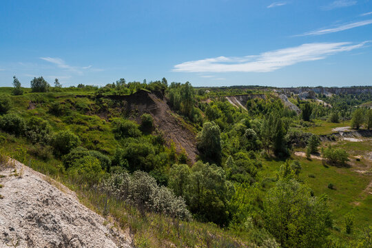 A beautiful summer landscape overlooking an old abandoned quarry and a race track deep in an abandoned quarry. Blue skies and clouds, trees and lots of greenery everywhere. High quality photo