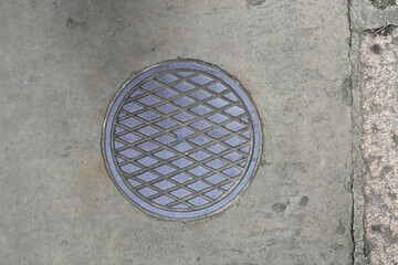 round manhole cover witj a diamond pattern on the sidewalk