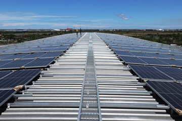 Fototapeta premium Solar PV Rooftop on Curve Roof under Construction with Walkway and Workers Background