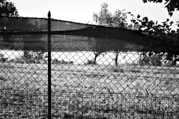 Metallic fence with a construction fabric in front of a garden in the italian countryside (Pesaro, Italy, Europe)
