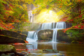 Fototapeta premium Sunny Autumn landscape - river waterfall in colorful autumn forest with old bridge