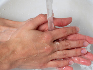 Fototapeta premium the girl washes her hands under a stream of water. Daily care and hygiene rules that protect against viruses and bacteria