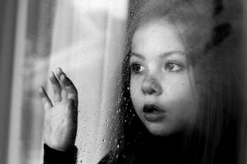 girl looks out the window and is sad