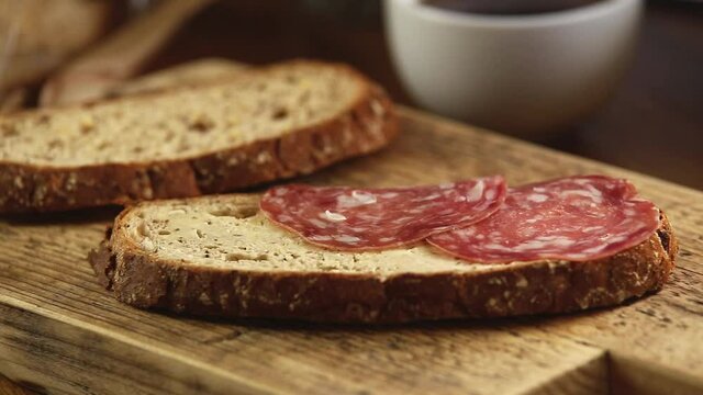 A delicious open sandwich with salami and cucumber, on rye bread. man hand