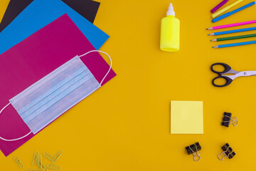 colored paper, colored pencils,markers, face mask, scissors, glue on a yellow background .back to...