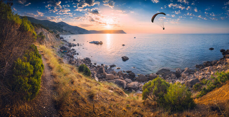 Fototapeta na wymiar Paraglider silhouette flying over the sea