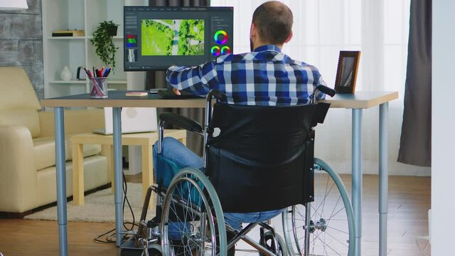 Disabled filmmmaker in wheelchair working on post production of a new video. Handicapped invalid paralysed freelancer, immobilized entrepreneur working from home, ilness and disability