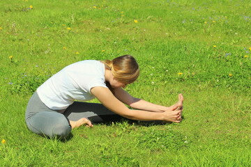 Young woman of European appearance does yoga in summer nature