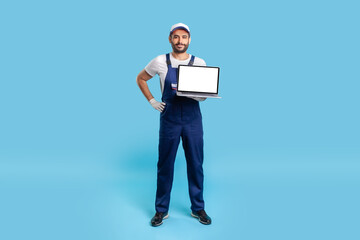 Full body portrait of confident professional expert repairman in workwear holding laptop with mock up blank display, empty place for advertise, message or repair service order. studio shot isolated