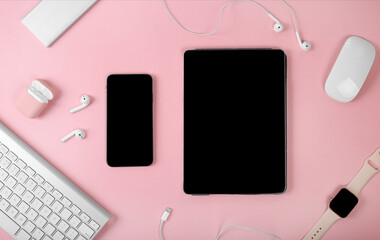 Mockup of smart gadgets on the background of office items on pink background. Mockup of tablet and smartphone. Computer mouse and keyboard, headphones, smart watch and powerbank. Woman devices