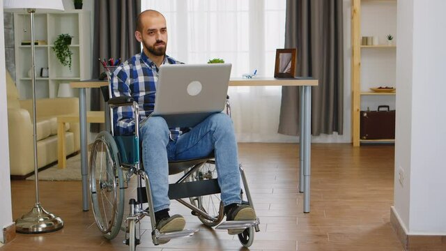 Invalid businessman in wheelchair working on laptop from home office. Handicapped invalid paralysed freelancer, immobilized entrepreneur working from home, ilness and disability