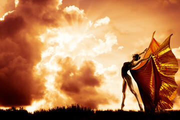 Woman Dance in Wings Costume Flying over Sunset Sky, Beautiful Girl Dancing in Sun Rays over Clouds...