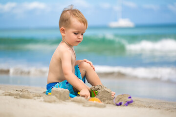 Cute baby boy playing with beach toys on tropical beach