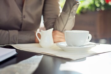 Coffee with milk, table in summer outdoor restaurant, business woman at table