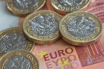 British pound coins set on a Euro note. Selective focus , close up view.