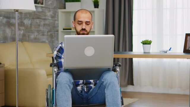 Invalid man in wheelchair working on laptop from home. Handicapped invalid paralysed freelancer, immobilized entrepreneur working from home, ilness and disability