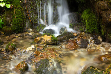 Calming natural waterfall with small stones and moss