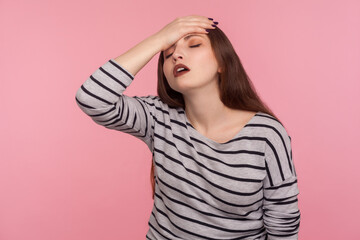 Facepalm. Portrait of upset woman in striped sweatshirt holding hand on forehead, blaming herself for forgotten event, bad memory, feeling sorrow and shame. studio shot isolated on pink background