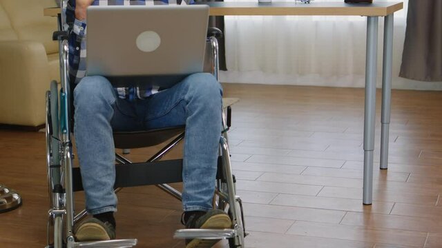 Disabled entrepreneur in wheelchair working from home on laptop. Handicapped invalid paralysed freelancer, immobilized entrepreneur working from home, ilness and disability