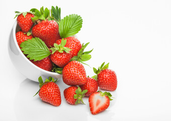Fresh raw organic strawberries in white ceramic bowl plate on white background with berries next to it.