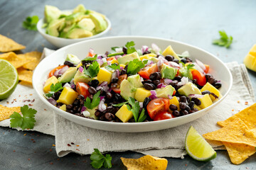 Avocado, mango salad with black bean, tomato, red onion and tortilla chips. healthy food