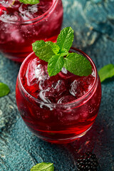 Refreshing Blackberry cocktail with ice and mint on rustic background