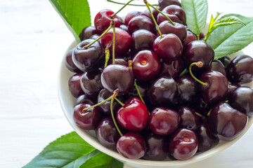 Cherry berries in a bowl on a white background. Fresh cherries. The concept of a healthy diet and support for local producers. Close-up. Top view.