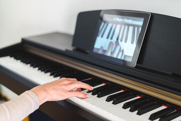 caucasian woman learning to play piano with video lessons. Concept of virtual learning © dzmatph