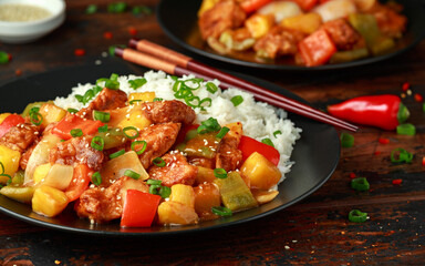 Pineapple and Chicken in sweet and sour sauce with bell pepper, rice and spring onion on wooden table