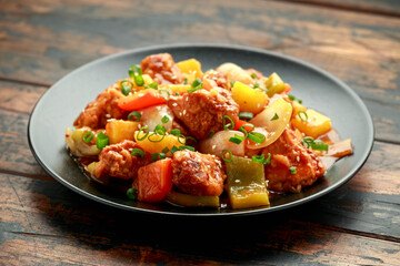 Pineapple and Chicken in sweet and sour sauce with bell pepper, rice and spring onion in black plate