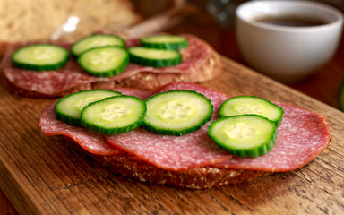 Rye Bread open sandwich with salami, cucumber on wooden board