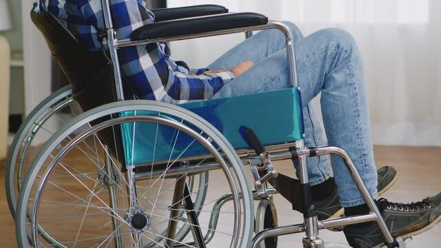 Man with walking disability sitting sad in wheelchair. Handicapped invalid paralysed person, alone at home, depression and health problems, pensive, sad and unhappy man