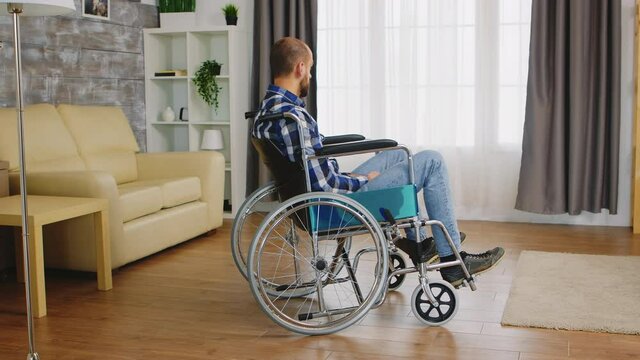 Invalid young guy and depressed in wheelchair. Handicapped invalid paralysed person, alone at home, depression and health problems, pensive, sad and unhappy man