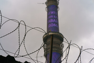 Ostankino tv tower through Barbed wire.  High technology in everyday. Telephoto lens. Transl. of  inscription - Stay home. Take care of yourself. Coronavirus pandemic.