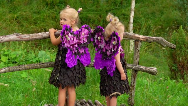 Beautiful girls with purple butterfly wings are standing on the wooden bridge outdoors