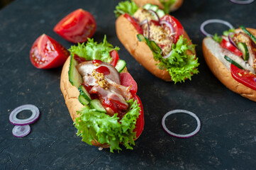 Hot dogs with different fillings. View from above. Against a dark background. Flat lay.