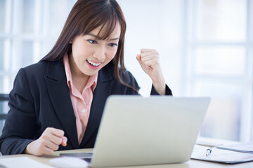 Beautiful Asian business woman wore a black suit sitting in the office, smiling happily when the job project was successful. Asian business women, business owners and office workers.