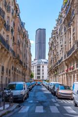 Obraz premium Montparnasse Tower at the End of a Narrow Parisian Street with Cars