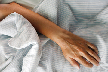 A hand on the bed sheets, close up