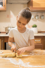 Little girl cooks pastry rolls