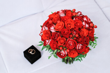 beautiful wedding bouquet of red roses on a white background with rings in a blurred background