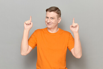 Portrait of happy cheerful man raising index fingers up and smiling